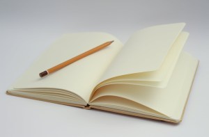 A pencil resting on the blank page of a notebook