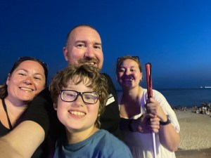 At night, a family selfie with the beach at Nice behind us and the moon reflecting off the sea