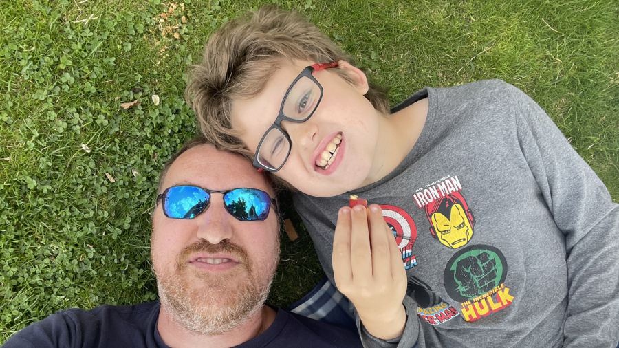 A selfie of a father and child lying on the grass